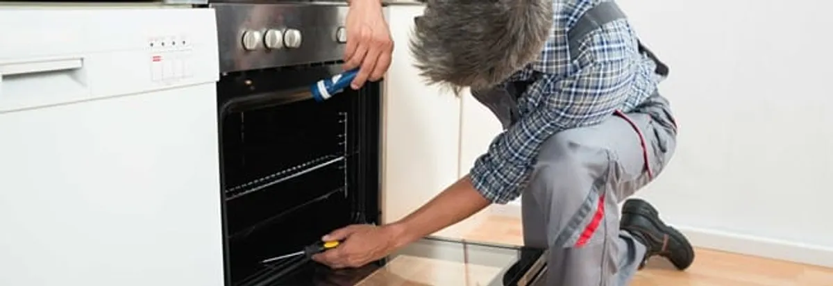 Oven repair technician inspecting and servicing an electric oven in Green Bay, WI