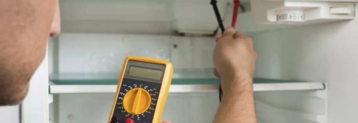 Refrigerator repair technician testing electrical components with a multimeter in Green Bay, WI