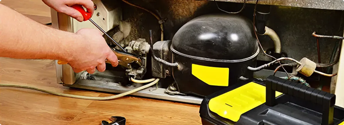Refrigerator repair technician fixing the compressor and wiring in Green Bay, WI